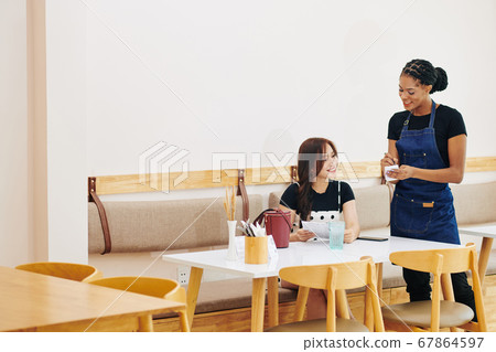 Waitres talking to customer Waitres talking to customer 67864597