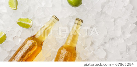 Chilled drink for summer heat. Glass bottles with light beer without labels in ice with pieces of lime 67865294