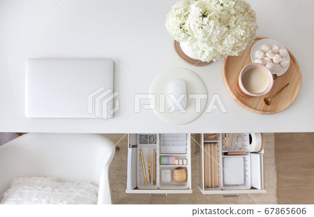 The gold stationery is neatly arranged in white containers in the drawers of the nightstand. Storage and tidying up the workplace. 67865606