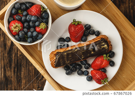 Eclair cake with chocolate glaze on wooden tray 67867026