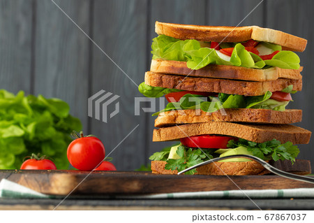 Healthy sandwich with vegetables on dark wooden background Healthy sandwich with vegetables on dark wooden background 67867037