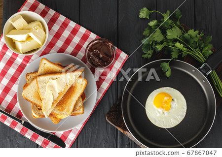 Fried egg in frying pan with sliced bread on wooden table Fried egg in frying pan with sliced bread on wooden table 67867047