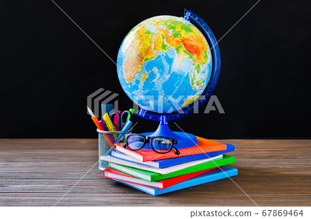 Back to school. Stack of books, school supplies, globe and glasses on black board background. Back to school. Stack of books, school supplies, globe and glasses on black board background. 67869464