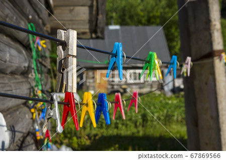 Clothespins on clothesline in village on background of old wooden country hut Clothespins on clothesline in village on background of old wooden country hut 67869566