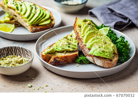 Avocado toasts with seeds on a gray plate.  67870032