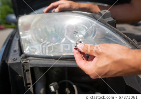 Young man hands changing car bulb or flashbulb of the front headlight or headlamp, repairing car concept 67873061