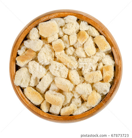 Dry bread cubes for stuffing, in a wooden bowl. Made of rolls, cut into cubes and dried, used for bread stuffing recipes like bread dumplings or stuffed turkey. Close-up from above, macro food photo. Dry bread cubes for stuffing, in a wooden bowl. Made of rolls, cut into cubes and dried, used for bread stuffing recipes like bread dumplings or stuffed turkey. Close-up from above, macro food photo. 67873723