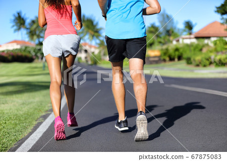 Runners running on road - closeup of legs of athletes sprinting training cardio together 67875083