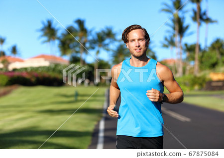 Running athlete man runner training cardio on road for marathon run. Athletic fit young sport fitness model outside in tropical summer city 67875084