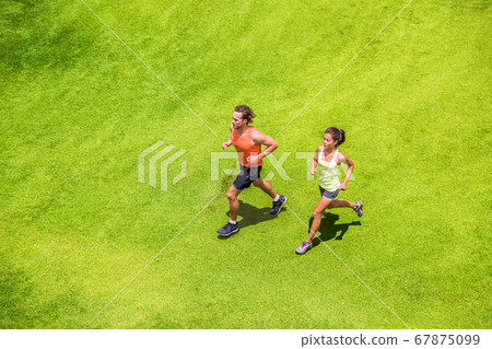 Runners running healthy people lifestyle. Active couple jogging together on grass park view from above. Summer weight loss training program 67875099