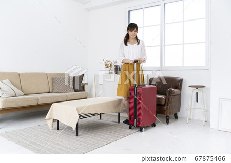A woman preparing to go out by packing luggage in a carry bag A woman preparing to go out by packing luggage in a carry bag 67875466