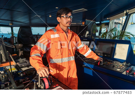 Filipino deck Officer on bridge of vessel or ship. He is speaking on GMDSS VHF radio Filipino deck Officer on bridge of vessel or ship. He is speaking on GMDSS VHF radio 67877483