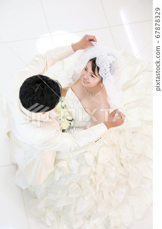 Bride and groom in a wedding dress and tuxedo photo a scene to raise the wedding veil 67878329