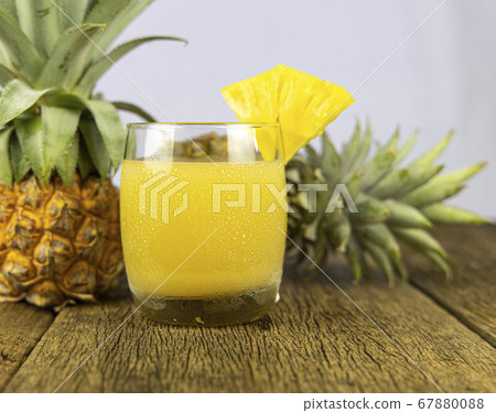 A glass of pineapple juice on wooden table 67880088