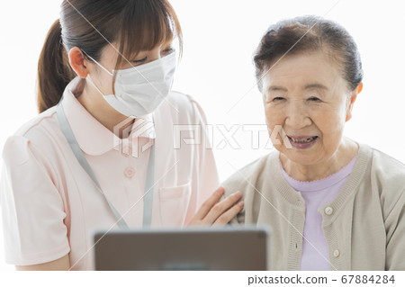 Senior woman making a video call and their assistance staff 67884284