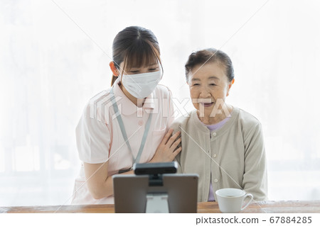 Senior woman making a video call and their assistance staff 67884285