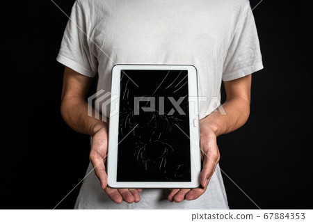 Person holding a tablet with a cracked screen Person holding a tablet with a cracked screen 67884353