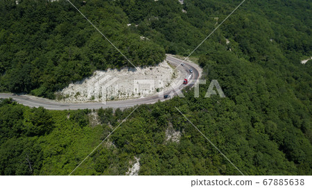 Aerial view from drone of curve road with a car on the mountain with green forest in Russia 67885638