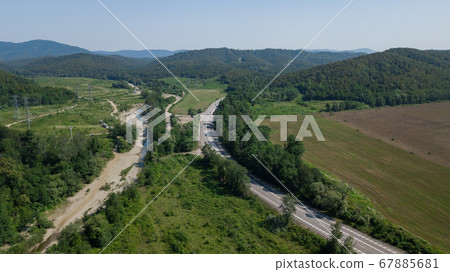 Aerial view from above of curve highway road with a car with green forest in Russia Aerial view from above of curve highway road with a car with green forest in Russia 67885681