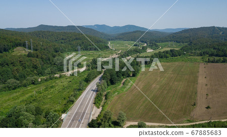 Aerial view from above of curve highway road with a car with green forest in Russia 67885683