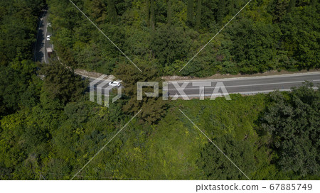 Aerial view from drone of curve road with a car on the mountain with green forest in Russia 67885749