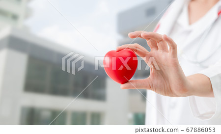 Doctor holding a red heart at hospital office. 67886053