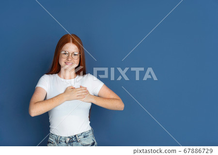Caucasian young girl's portrait isolated on blue studio background. Beautiful female model. Concept of human emotions, facial expression, sales, ad, youth culture. Caucasian young girl's portrait isolated on blue studio background. Beautiful female model. Concept of human emotions, facial expression, sales, ad, youth culture. 67886729