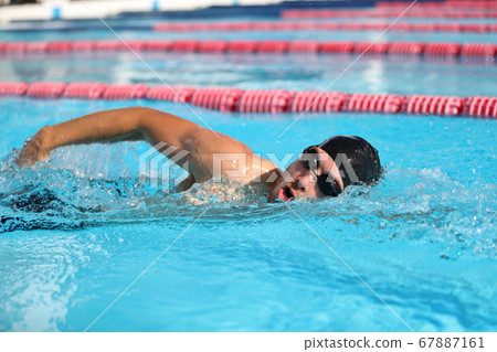 Swim competition swimmer athlete doing crawl stroke in swimming pool. Sports man male swimmer with goggles and cap breathing racing in indoor stadium. Speed exercise workout 67887161