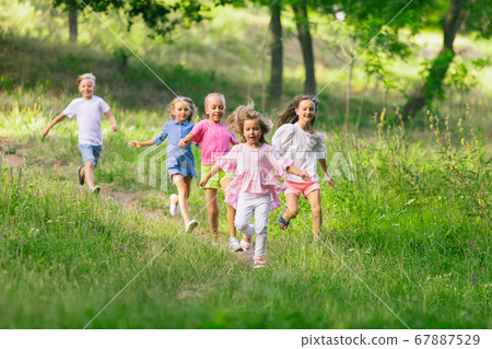 Kids, children running on meadow in summer's sunlight 67887529