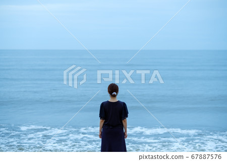 A woman standing on the edge of the beach 67887576
