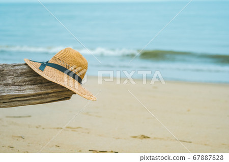 Sea, driftwood and straw hat 67887828