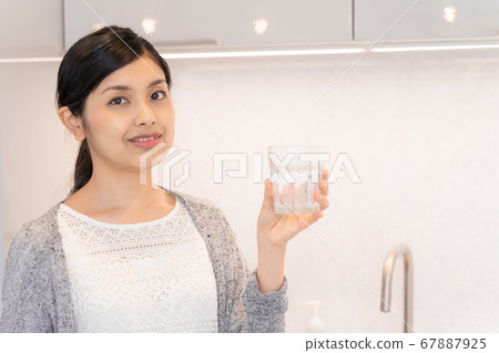 年輕女子在廚房裡有礦泉水 67887925