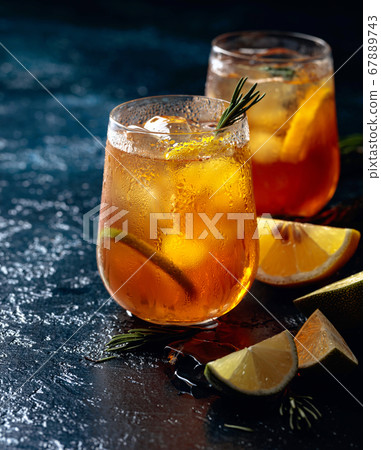 Traditional iced tea with lemon, lime and ice garnished with rosemary twigs. Traditional iced tea with lemon, lime and ice garnished with rosemary twigs. 67889743