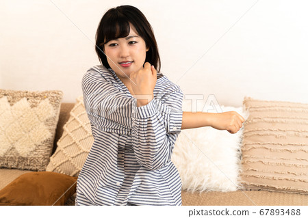 Young housewife sitting on the sofa in pajamas Young housewife sitting on the sofa in pajamas 67893488