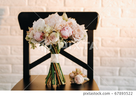 wedding bouquet with peonies and roses on a chair and boutonniere.The decor at the wedding 67893522