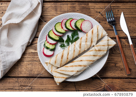 Roll with cheese and herbs. Grilled pita bread with filling. Cucumber radish salad. The concept of a healthy Breakfast. Roll with cheese and herbs. Grilled pita bread with filling. Cucumber radish salad. The concept of a healthy Breakfast. 67893879