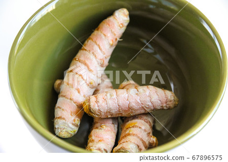 Turmeric root in a bowl isolated on white Turmeric root in a bowl isolated on white 67896575