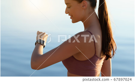 Woman standing on the beach, looking at tracker 67897024