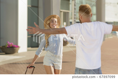 Boyfriend picking up his girlfriend near airport building 67897099