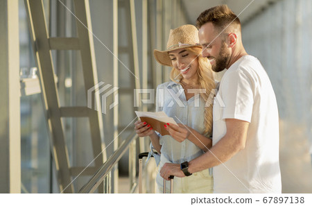 Travel concept. Couple checking tickets at airport Travel concept. Couple checking tickets at airport 67897138