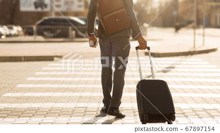 Unrecognizable Gentleman With Travel Suitcase Crossing Road Outdoor, Panorama, Rear-View Unrecognizable Gentleman With Travel Suitcase Crossing Road Outdoor, Panorama, Rear-View 67897154