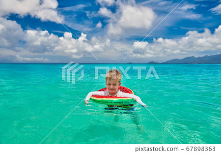 Toddler boy on beach swimming with inflatable ring Toddler boy on beach swimming with inflatable ring 67898363