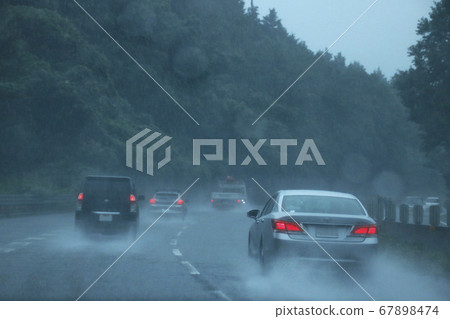 Several cars driving on a highway in heavy rain 67898474