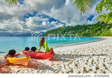 Woman sitting on kayak at beach, Seychelles, Mahe 67898690