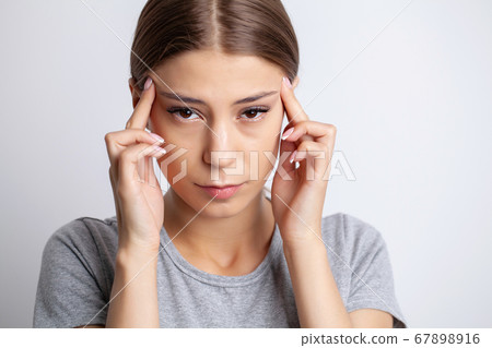A young woman has a severe headache 67898916