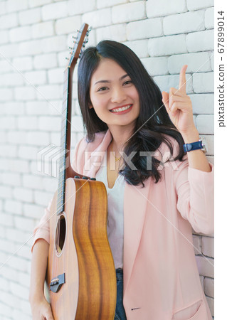 young woman playing guitar in living room, Enjoying carefree time at home. 67899014