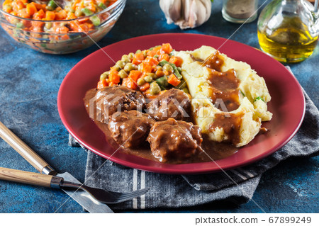 Roasted meatballs in dark sauce with mashed 67899249