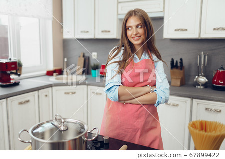 Nice young woman cooking something by the stove in her kitchen 67899422