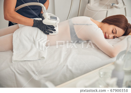 Brunette female enjoying time during skincare procedure Brunette female enjoying time during skincare procedure 67900358