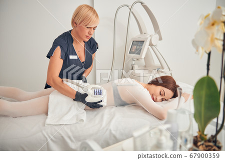 Beautiful brunette female relaxing at beauty salon in special clothes Beautiful brunette female relaxing at beauty salon in special clothes 67900359